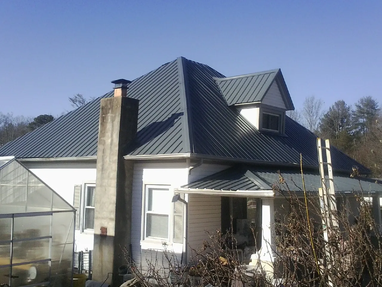 Dark blue standing seam metal roof on a white farmhouse with dormer — Slate & Tile Roof Repair by Roofing Brothers in Stevenson Ranch