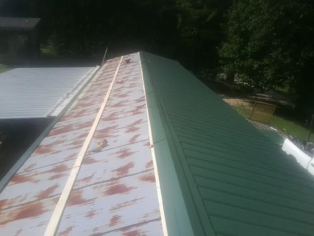 Old rusted panels beside newly installed green metal roofing — Wind Damage Roof Repair by Roofing Brothers in Stevenson Ranch