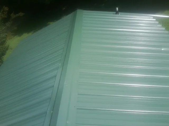 New green metal panels meeting at the ridge of a roof — Flat Roof Repair work by our crew in Stevenson Ranch